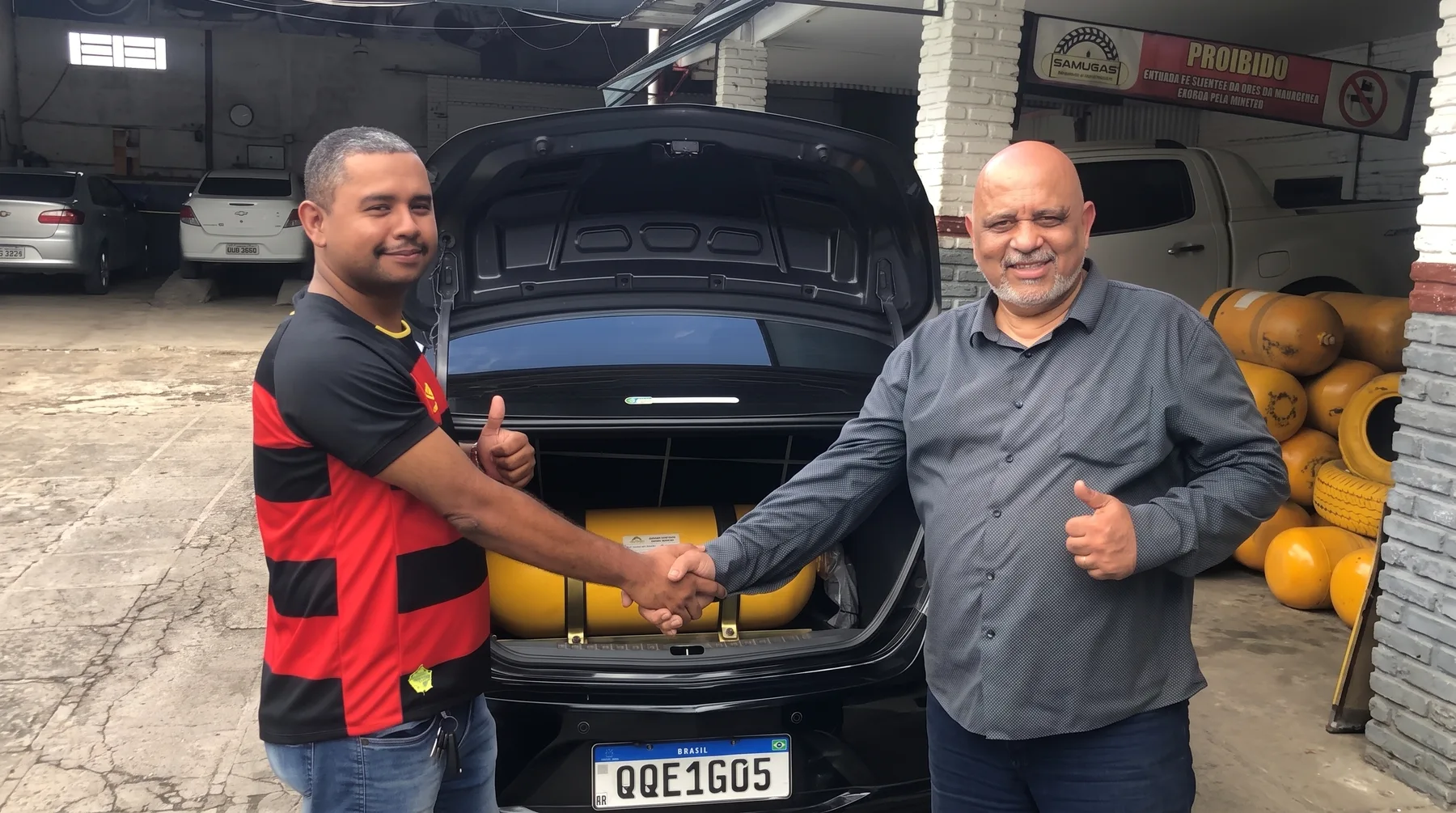 Cliente e representante da Samugás apertando as mãos em frente ao veículo após a instalação de GNV
